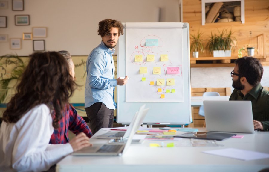 Man teaching others in front of a diagram